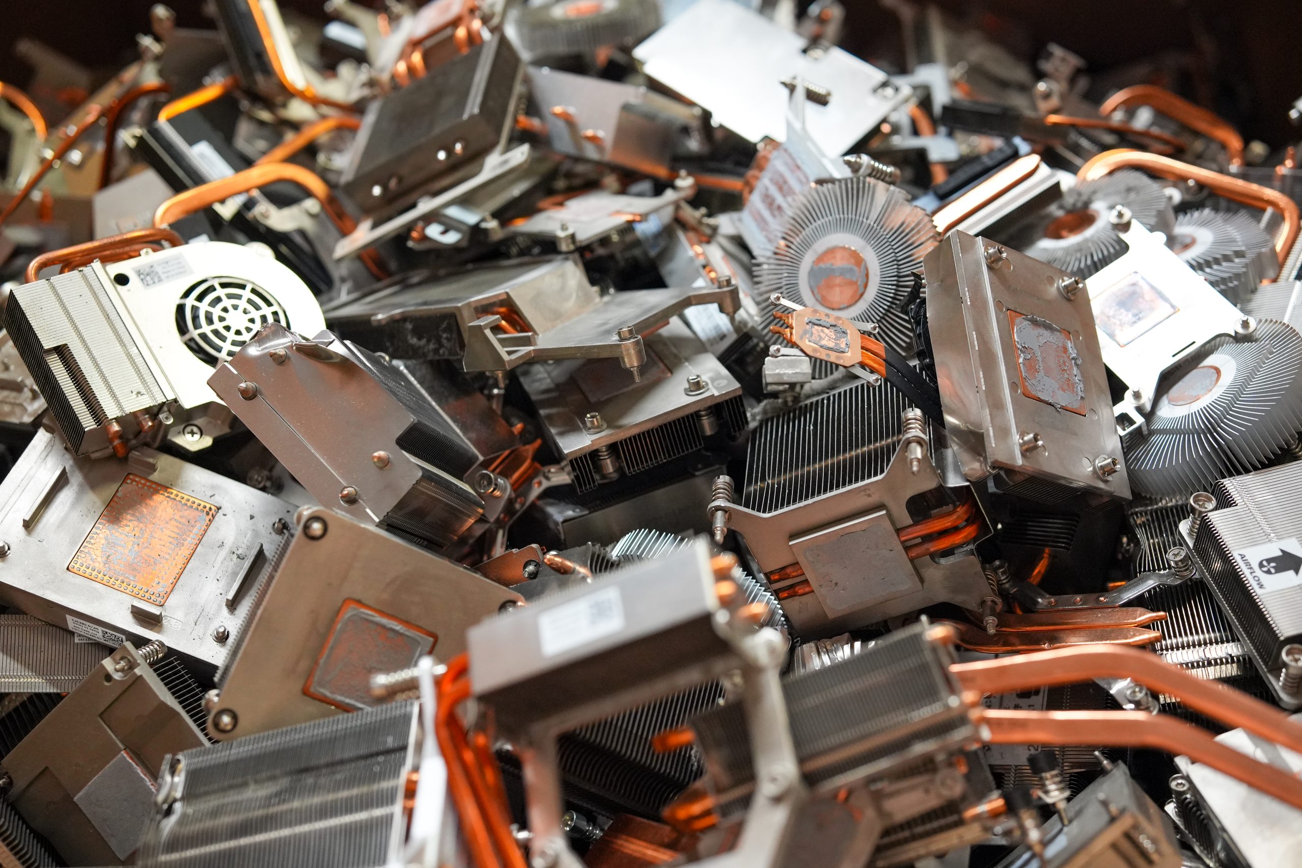 A pile of computer heat sinks and cooling fans, predominantly copper and metallic in color, with visible fins and heat pipes. The disorganized components hint at scrap or recycled parts, perfect for those seeking free electronics pickup in Central PA and surrounding areas.