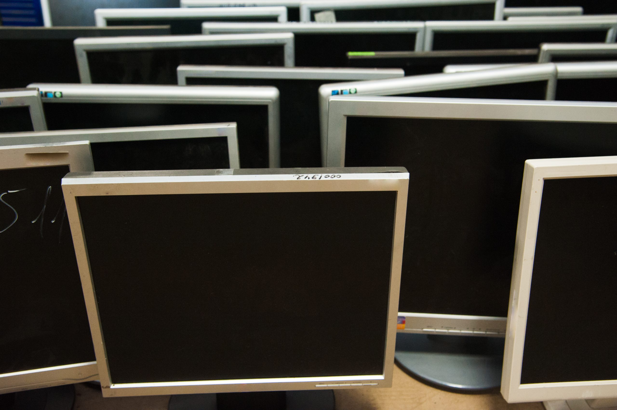 Rows of turned-off computer monitors running Windows 10 are closely arranged, creating a pattern of blank black screens and silver frames—an image that hints at cybersecurity vigilance in a quiet workspace.